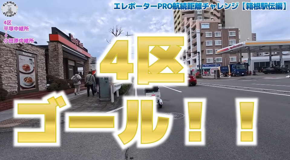 2026-05-04_173411 | ELEMOs Video thumbnail with large yellow text '4区ゴール!!' over a street scene, showing a cafe on the left and city buildings with cars on the road.