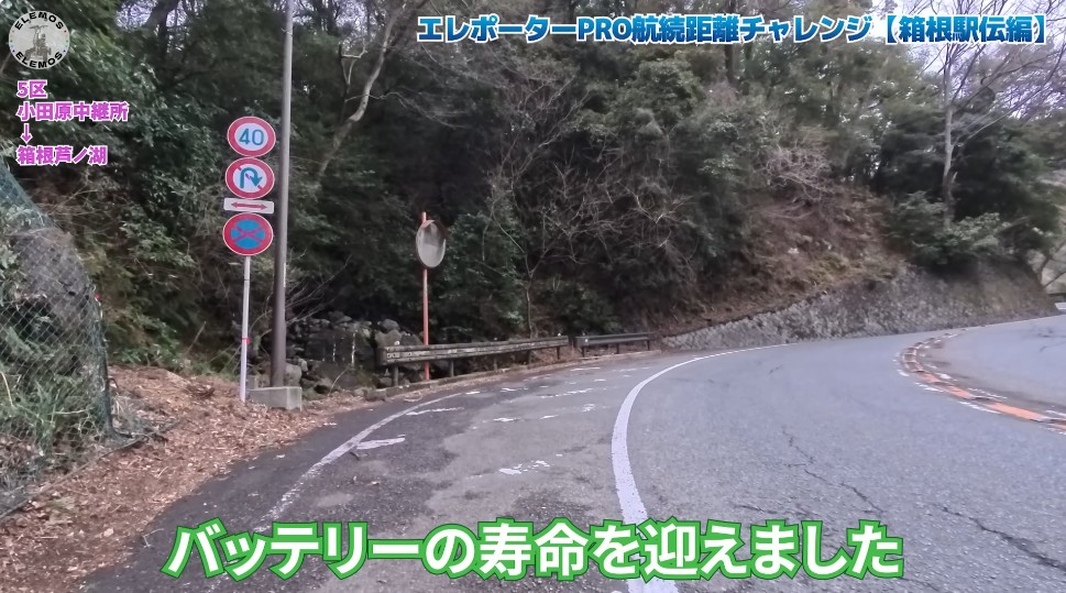 2026-05-04_182113 | ELEMOs Winding mountain road beside a wooded hillside with traffic signs on the left and a guardrail, as a video thumbnail with Japanese captions.