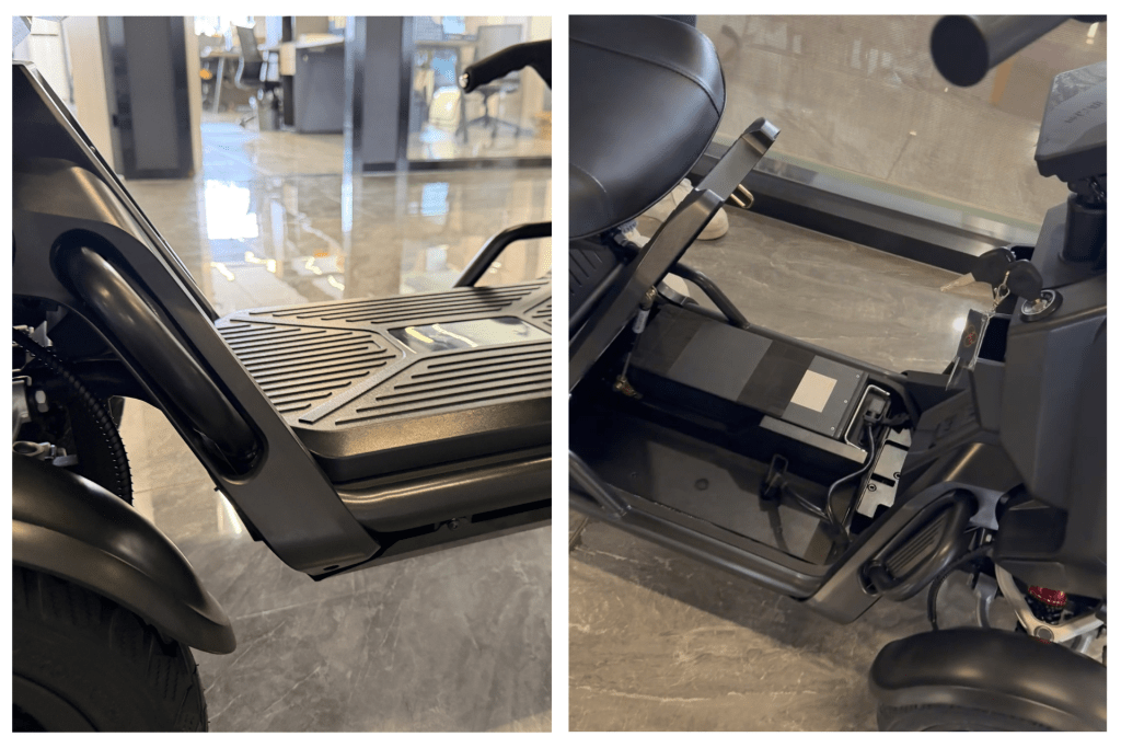 Close-up of a black scooter's textured footboard and front panel, with a showroom floor in the background.