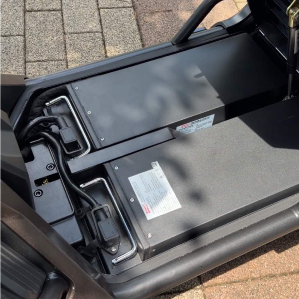 Close-up of an electric scooter battery bay with wiring and a safety label visible on the pack.