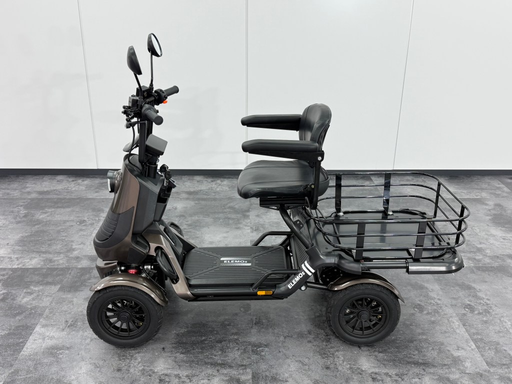 Electric mobility scooter with padded seat and rear cargo rack parked indoors on gray tile floor.