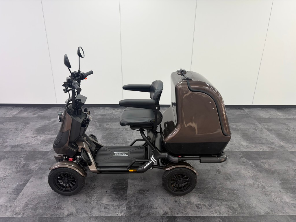 Electric mobility scooter with brown housing, black seat, and handlebars in a showroom.